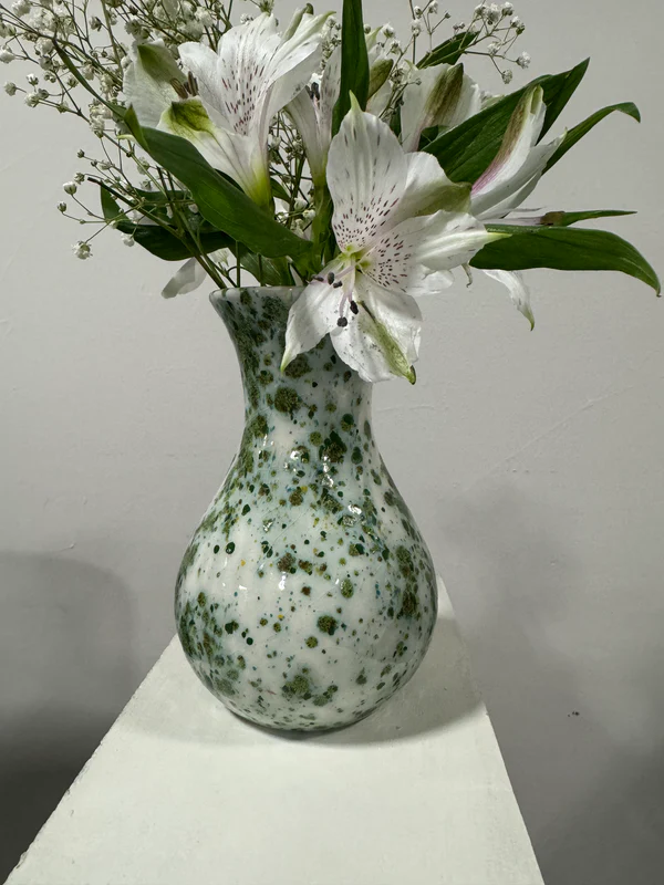 The Amanda Vase is pictured and holds a bouquet of flowers. It is a light green vase with a green spotted pattern on it.