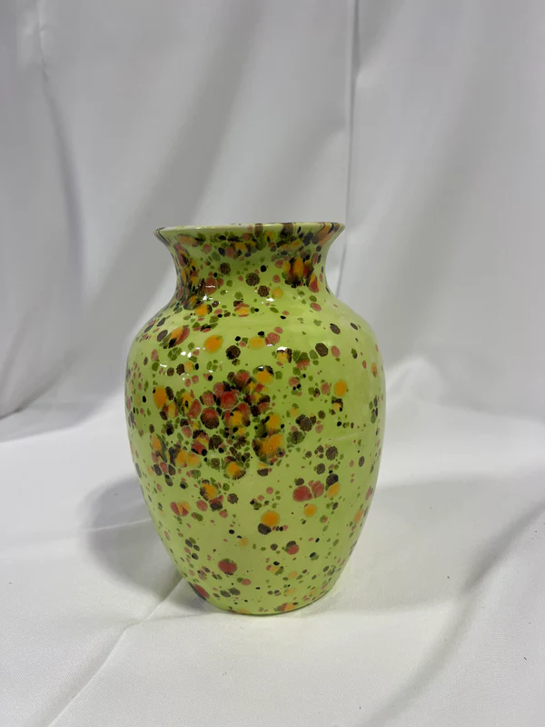 The Juliana Vase is pictured. It is a green vase with red and orange splatters of paint on it.