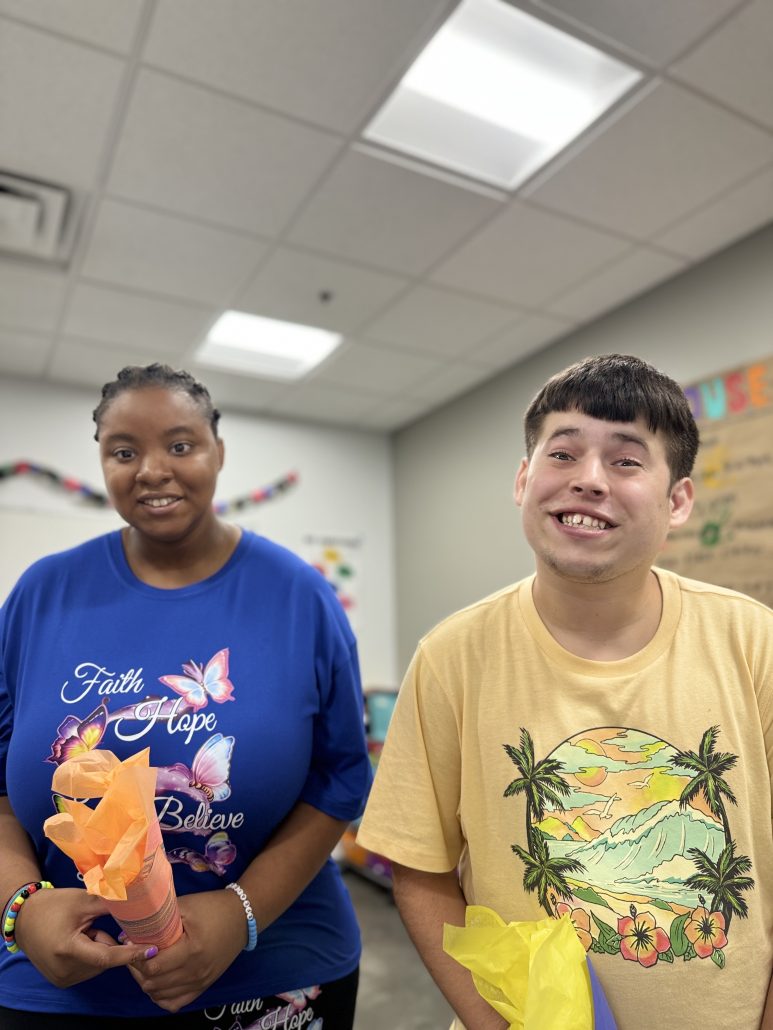 A man in a yellow shirt and a woman in a blue shirt smile.