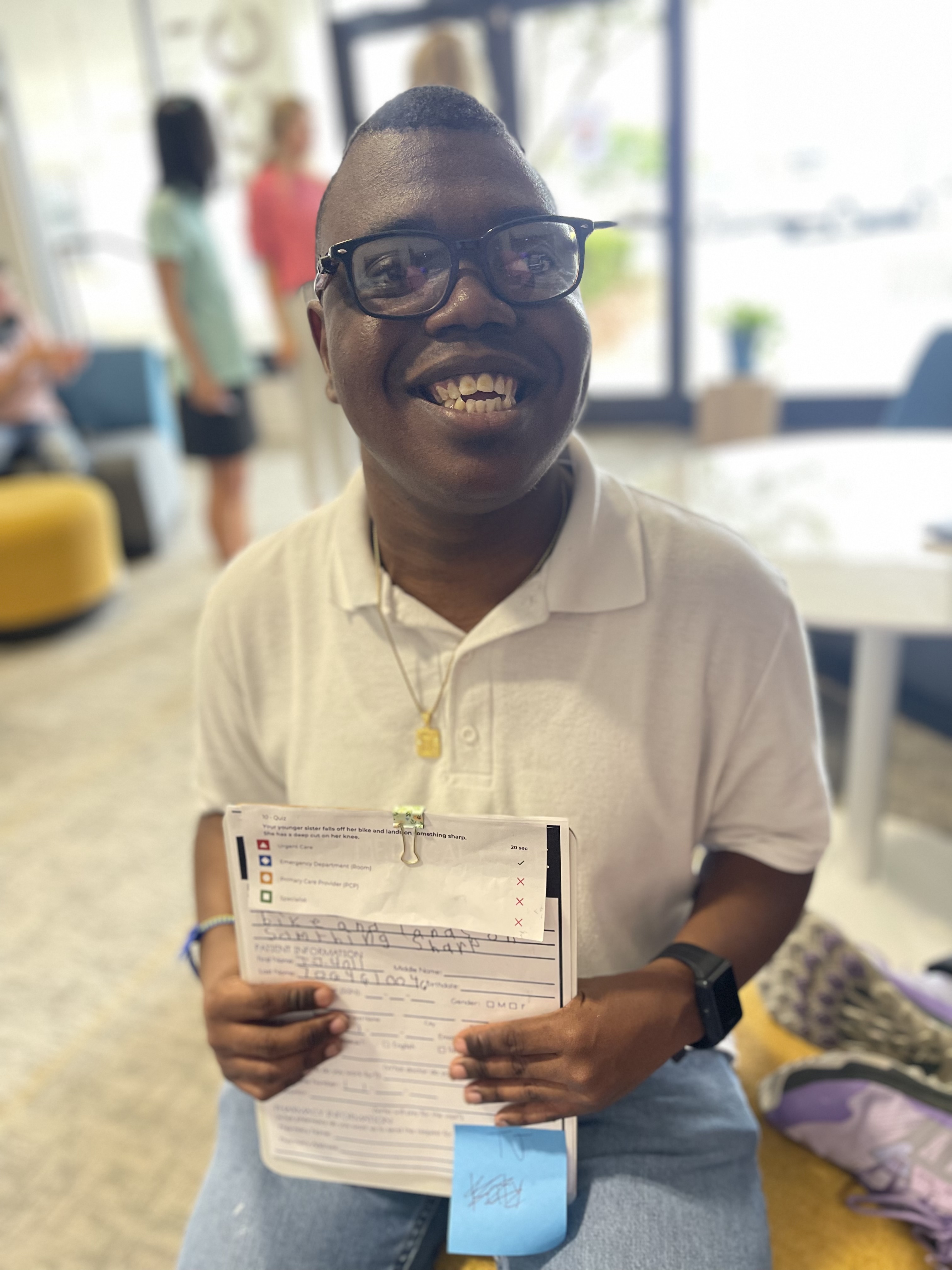 A man in glasses smiles and holds up a form.