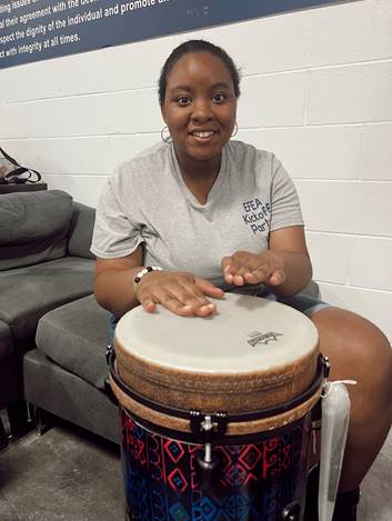 Smiling woman playing a drum.