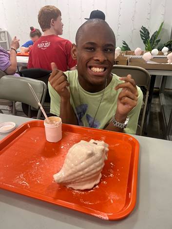 Smiling man with shell sculpture.